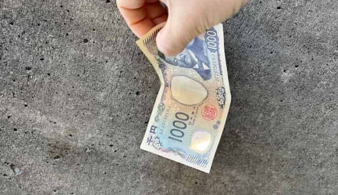 1,000円を拾っている手